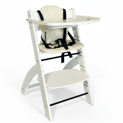 En justerbar høy barnestol i tre, hvit farge, utstyrt med en hvit pute og sikkerhetssele. Den har et avtagbart brett og er vist sammenfelt med fotbrettet ute.