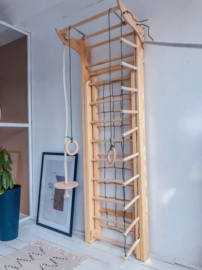 A wooden wall climbing ladder with a rope and ring hanging apparatus, shown in a home interior setting.